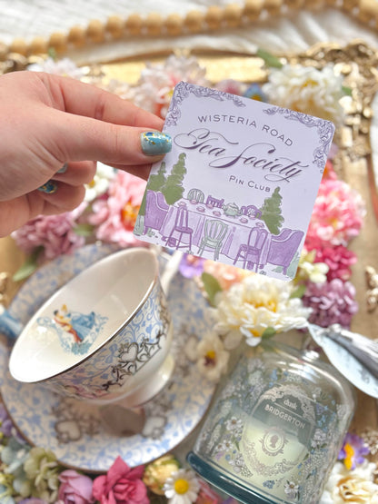 Wisteria Road Tea Society Pin Club April edition pin featuring a delicate floral design on a silver-tone metal background.
